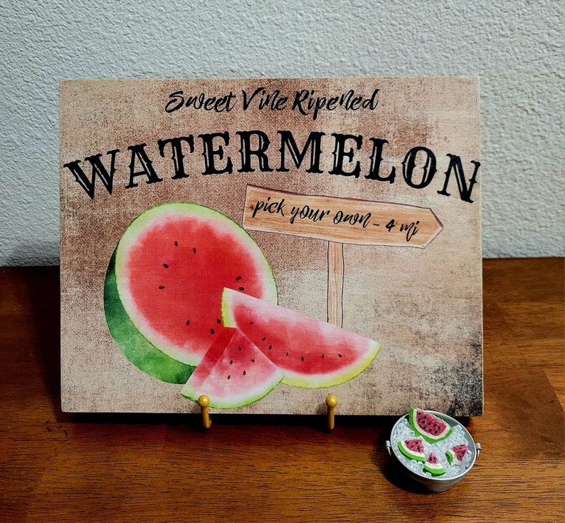Pode incluir: Uma placa de madeira r&uacute;stica com o texto "Sweet Vine Ripened Watermelon - pick your own - 4 mi" e uma ilustra&ccedil;&atilde;o em aquarela de fatias de melancia.