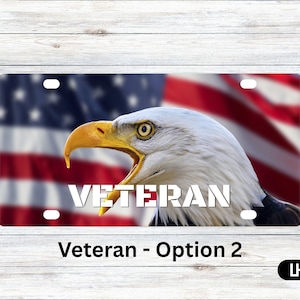 Könnte beinhalten: Kfz-Kennzeichen mit einem Weißkopfseeadler und der amerikanischen Flagge im Hintergrund. Das Wort "VETERAN" steht in weißen, fetten Buchstaben. Der Text "Veteran - Option 2" steht unten.
