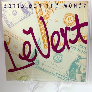 May include: A LeVert album cover with a background of dollar bills. The words "GOTTA GET THE MONEY" are at the top, and "LeVert" is in large, cursive, magenta letters. The album cover is in a clear plastic sleeve.