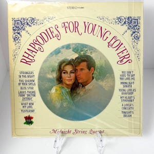 May include: Vintage vinyl record album titled "Rhapsodies for Young Lovers" by Midnight String Quartet. The cover features a couple in a circular image, with song titles listed on the left and right. The album is in a plastic sleeve.