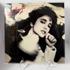 May include: Vinyl record album cover featuring a black and white portrait of a woman with dark hair. The album title, "Last Tango," is written in red script. The album is in a protective plastic sleeve.