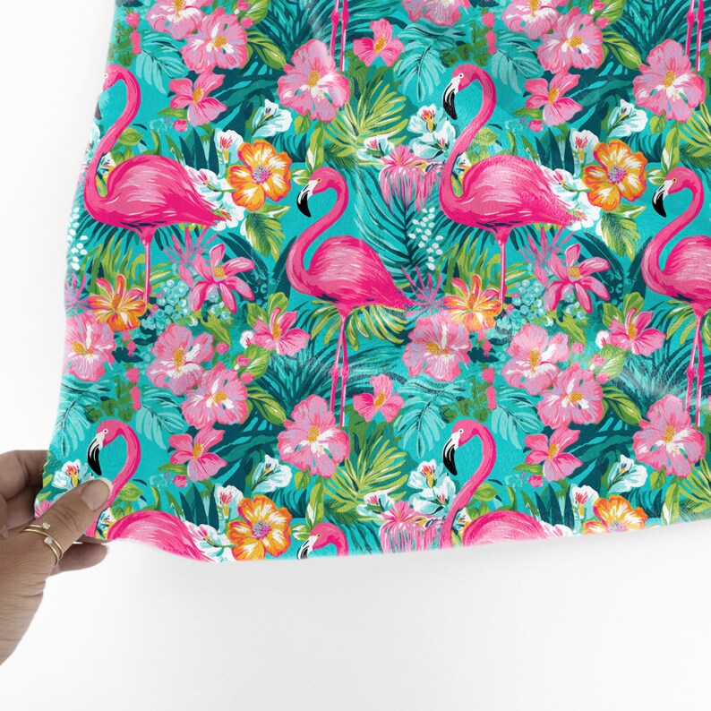 May include: A turquoise fabric with a tropical print featuring pink flamingos, green leaves, and pink and orange flowers.