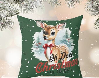 May include: A decorative square pillow with a green background and white polka dots. The pillow features a vintage illustration of a deer with a red bow, and the text "Oh Deer Christmas is HERE" in red.
