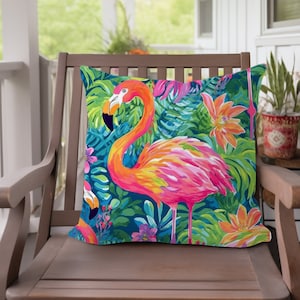 Op de afbeelding: Een levendig kussen met een roze flamingo die in een weelderige tropische jungle staat met groene bladeren en oranje bloemen. Het kussen is perfect om elke kamer een vleugje tropische flair te geven.