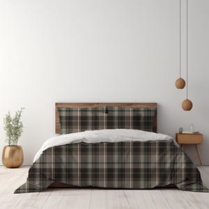 May include: A bedding set featuring a dark grey, brown, and white plaid pattern on the duvet cover and two matching pillowcases. The bedding is draped over a wooden bed frame with a headboard, creating a coordinated look for the sleeping area.