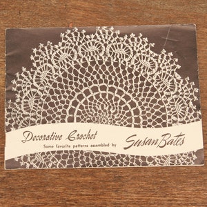 May include: A brown booklet with a white crochet pattern on the cover. The title reads "Decorative Crochet" and "Some favorite patterns assembled by Susan Bates".