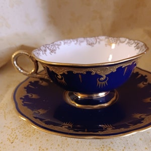 May include: A blue and gold teacup and saucer set. The cup and saucer are decorated with a gold floral pattern.