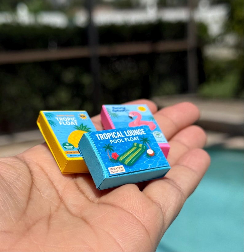 Miniature dollhouse pool float boxes, 1:12 scale summer beach accessories, tiny lounger float, donut float, flamingo float, mini pool props, handmade dollhouse decorations, dollhouse outdoor summer scene, dollhouse patio decor, realistic mini pool float packaging, collectible miniatures for dollhouse diorama, miniature summer float box set, dollhouse accessories for summer, mini beach toys, dollhouse swim party decor