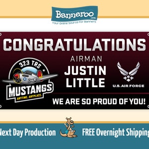 May include: A red banner with the text "CONGRATULATIONS AIRMAN JUSTIN LITTLE WE ARE SO PROUD OF YOU!"  The banner also features a vintage airplane logo with the text "323 TRS MUSTANGS ANYTIME, ANYPLACE." and a U.S. Air Force logo.