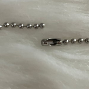 May include: A silver chain with a clasp. The chain is made of small, round links.