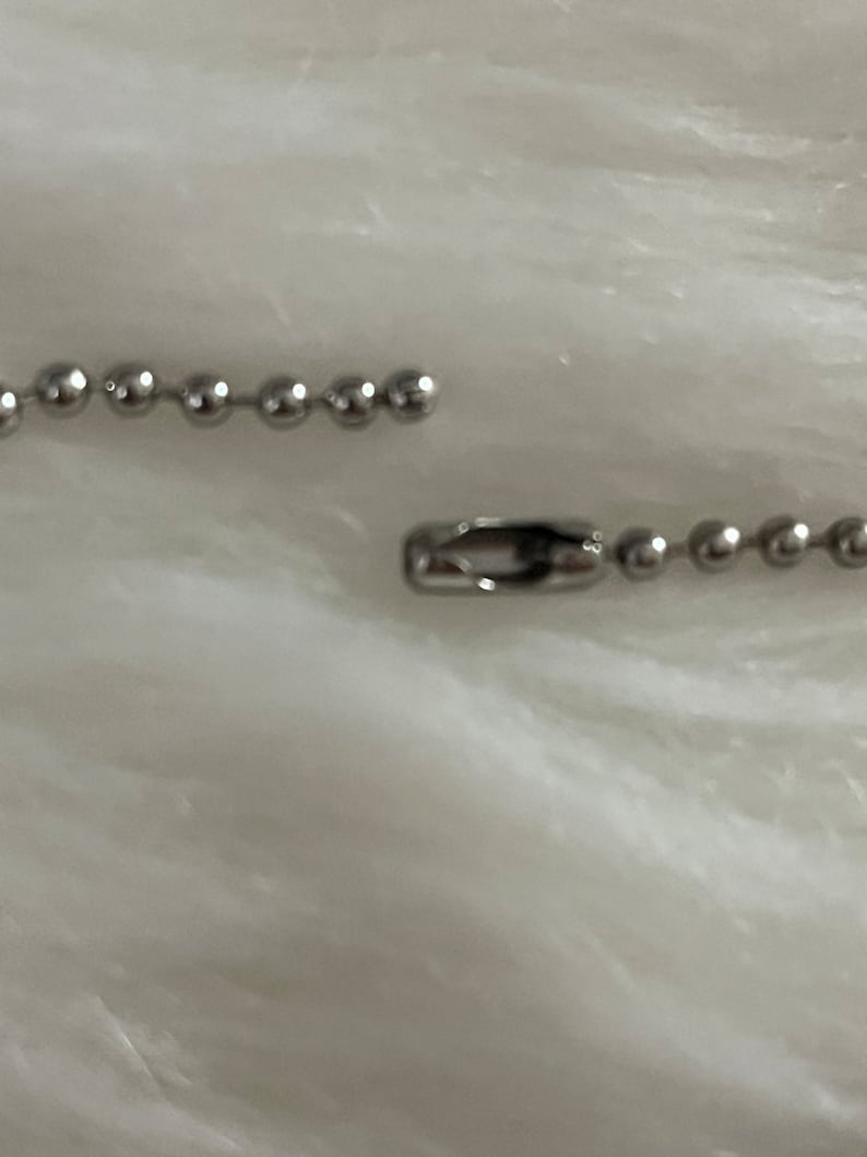 May include: A silver chain with a clasp. The chain is made of small, round links.