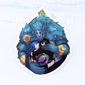 Puede incluir: Una pegatina que representa una figura humanoide de piel azul abrazando a dos personas. El humanoide tiene una apariencia peluda y detalles dorados. Una persona tiene trenzas azules y la otra tiene el pelo corto y negro. La pegatina tiene un fondo blanco.