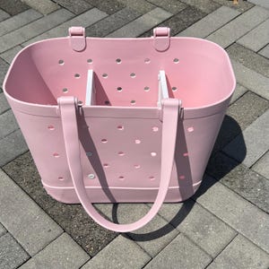 May include: A pink tote bag with white handles and a dotted pattern. The bag has two compartments inside.