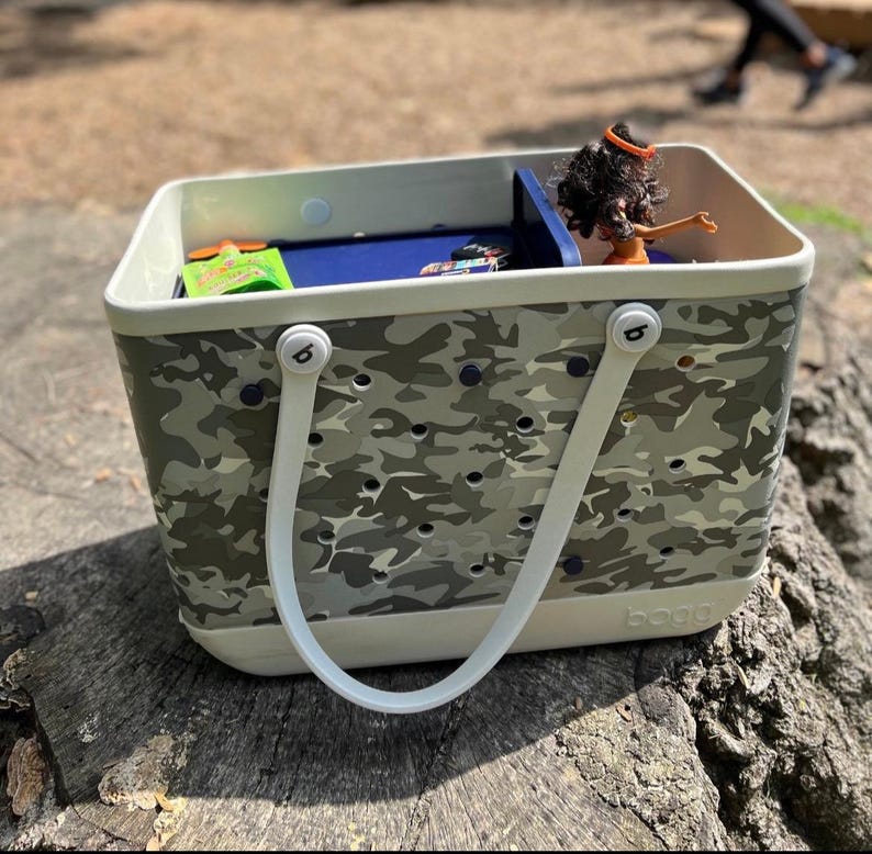 May include: A white and gray camo tote bag with white handles and a blue interior. The bag has a removable divider and a logo that says "b.o.b.b.e".