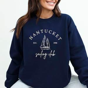 May include: A navy blue sweatshirt with a white graphic of a sailboat and the text "NANTUCKET Sailing Club Est. 1906".