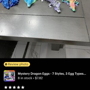 May include: Four colorful plastic dragon figurines, each with a different design and color, are displayed on a table. The dragons are posed in a variety of positions, with their tails curled up and their wings spread out. The dragons are all about 6 inches long and are made of a soft, flexible plastic. The dragons are part of a set of mystery dragon eggs, which are also shown in the image. The eggs are made of a hard plastic and are about 3 inches in diameter. Each egg contains a different dragon figurine. The eggs are sold in a set of 7, with 3 different egg types. The product is called "Mystery Dragon Eggs - 7 Styles, 3 Egg Types..." and is available for purchase on Etsy.