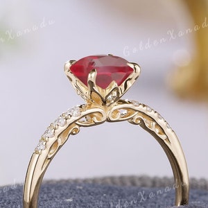 May include: A gold ring featuring a large red gemstone and smaller diamonds set in a delicate filigree design.