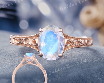 May include: A rose gold engagement ring with a large oval-shaped moonstone. The ring has a delicate floral design on the band.