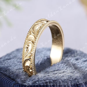 Może przedstawiać: Złoty pierścionek z bogatym wzorem kwiatowym. Pierścionek jest gładki i wypolerowany, z subtelnym połyskiem.