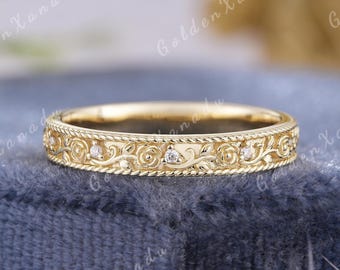 May include: A gold-colored ring with an intricate floral design and small, sparkling gemstones. The ring features a detailed pattern of swirling vines and flowers, with a rope-like border. The text "GOLDENXANADU" is at the top.