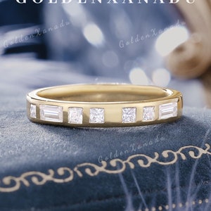 Könnte beinhalten: Ein Goldring mit einer Reihe kleiner, klarer, quadratischer und rechteckiger Diamanten.