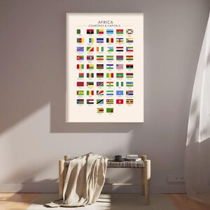 May include: A framed print showing the flags of African nations, labelled "AFRICA COUNTRIES & CAPITALS". The flags are arranged in a grid on a cream background. The print is displayed above a wooden bench with a draped blanket.