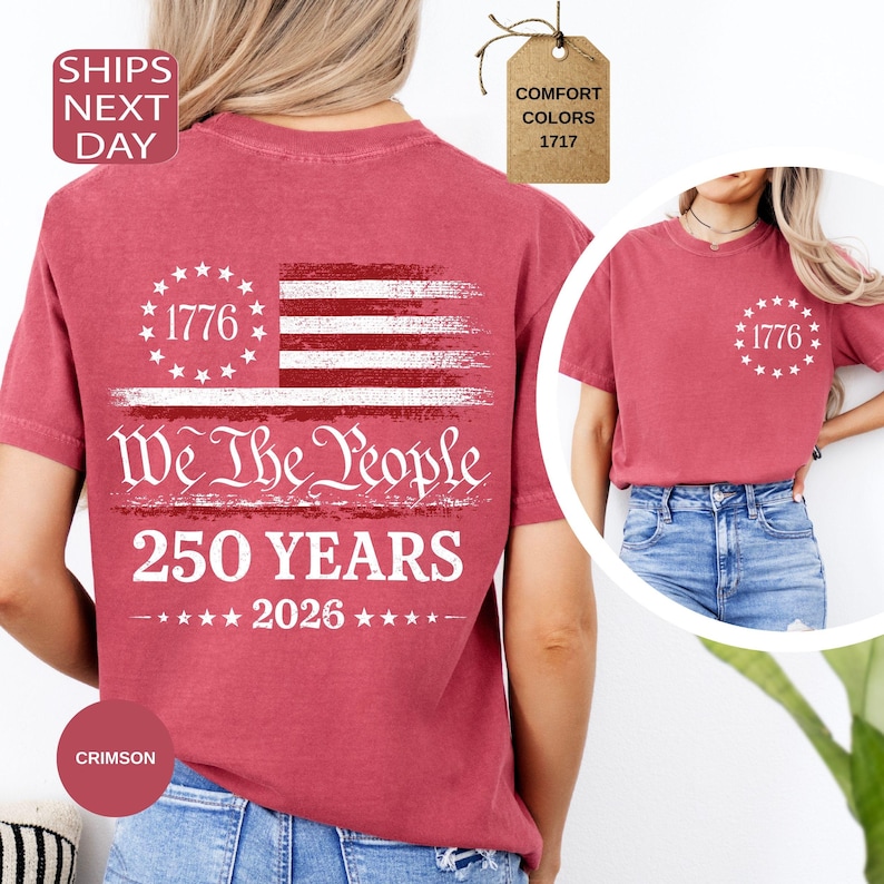 Pu&ograve; includere: T-shirt color cremisi con un design patriottico. Il design include il testo "1776", "We The People", "250 YEARS" e "2026", insieme a una bandiera americana stilizzata. Le t-shirt sono disponibili in colori comfort.