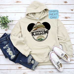 May include: A beige hoodie with a Mickey Mouse ear design featuring a safari hat and the words "Animal Kingdom" in a green circle.