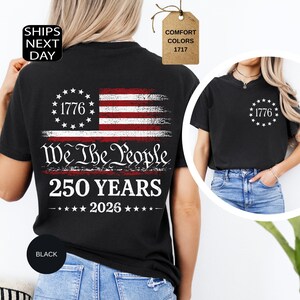 Pu&ograve; includere: T-shirt nero con un design invecchiato della bandiera americana. La maglietta presenta la scritta "1776" all'interno di un cerchio di stelle e "We The People 250 YEARS 2026" sotto. Girocollo e maniche corte.