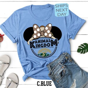May include: Light blue t-shirt featuring a graphic of Minnie Mouse wearing a safari hat and the text "Animal Kingdom".