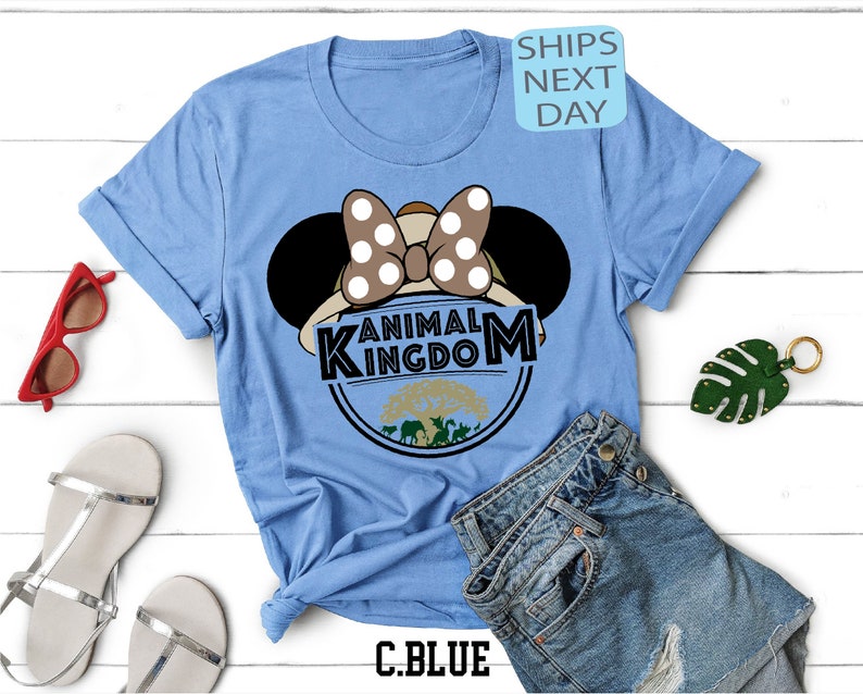 May include: Light blue t-shirt featuring a graphic of Minnie Mouse wearing a safari hat and the text "Animal Kingdom".