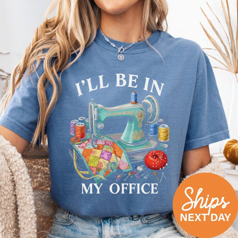 A woman wearing a blue t-shirt with a sewing machine graphic and the text "I'll be in my office" printed on it.