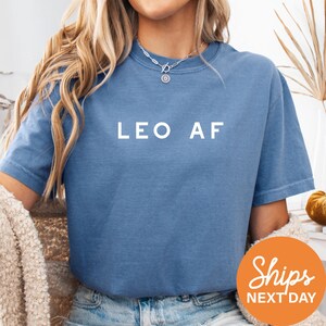 a woman wearing a blue leo af shirt