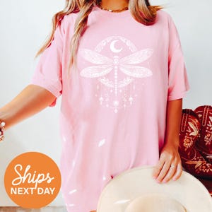 a woman wearing a pink shirt with a dragonfly on it