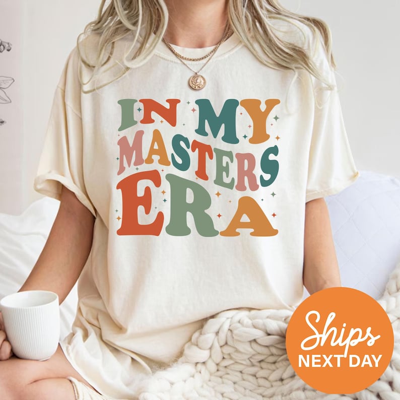 a woman sitting on a bed wearing a t - shirt that says in my masters