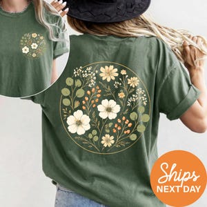 A woman wearing a green t-shirt with a floral design on the back.
