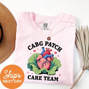 a pink shirt with a heart on it and a hat next to it