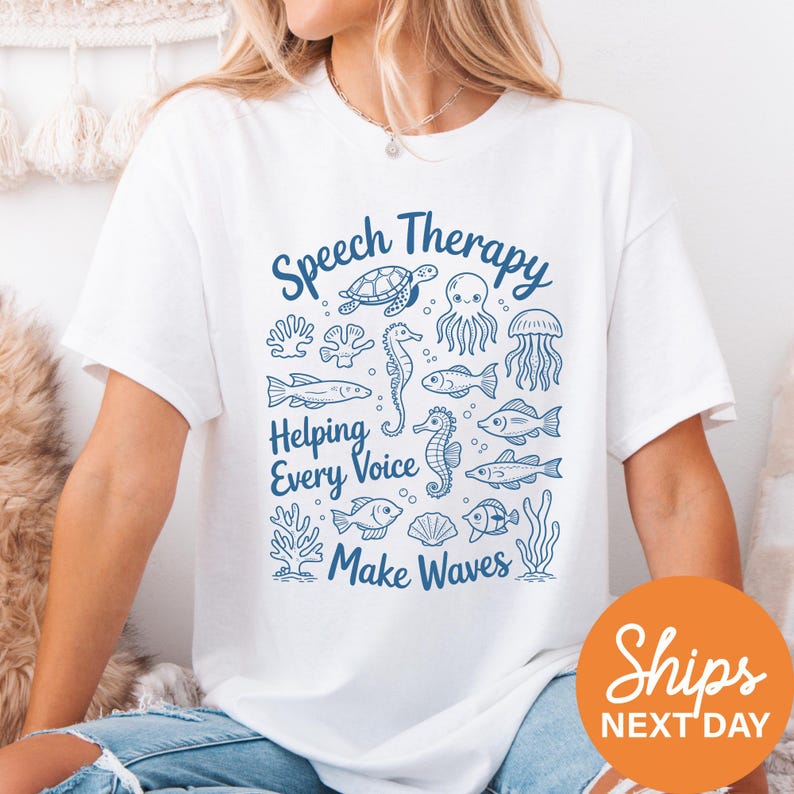 A woman wearing a white t-shirt with a graphic design featuring various sea creatures and the text "Speech Therapy Helping Every Voice Make Waves".