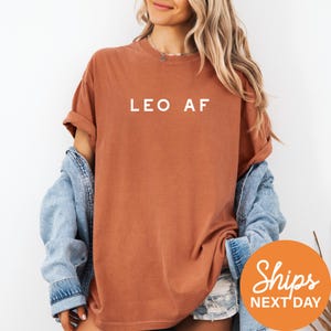 a woman wearing a brown leo af shirt