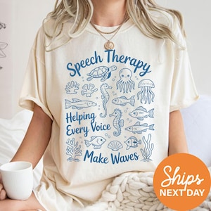 A person wearing a white t-shirt with a graphic design featuring various sea creatures and the text "Speech Therapy Helping Every Voice Make Waves" printed on it.
