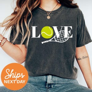 a woman wearing a t - shirt with a tennis ball on it