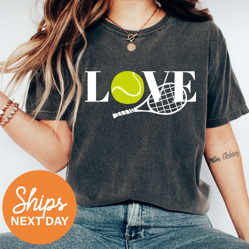 a woman wearing a t - shirt with a tennis ball on it
