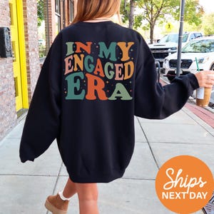 a woman walking down a sidewalk wearing a sweatshirt