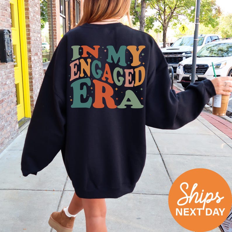 a woman walking down a sidewalk wearing a sweatshirt
