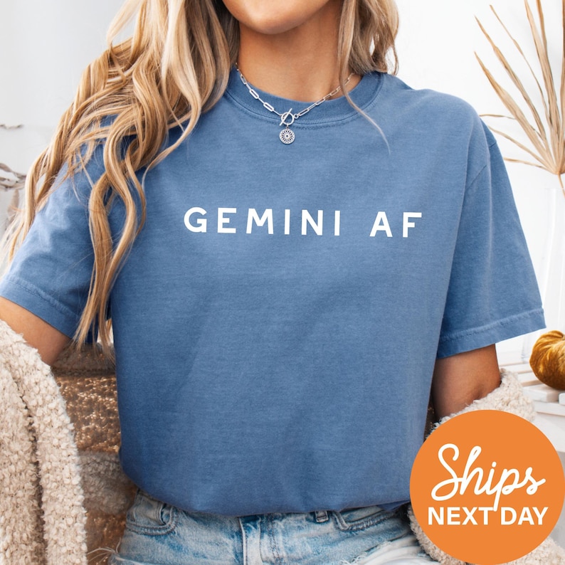 a woman wearing a blue shirt with the word gemin af on it