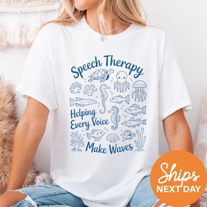 A woman wearing a white t-shirt with a graphic design featuring various sea creatures and the text "Speech Therapy Helping Every Voice Make Waves".