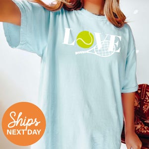 a woman wearing a blue shirt with a tennis ball on it