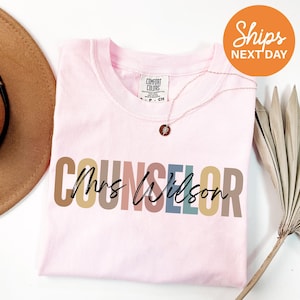 a pink shirt with the word's name on it next to a hat and