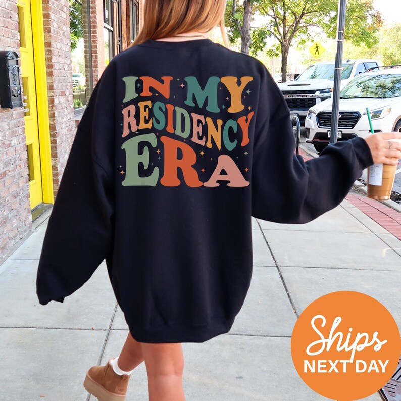 a woman walking down a sidewalk wearing a sweatshirt