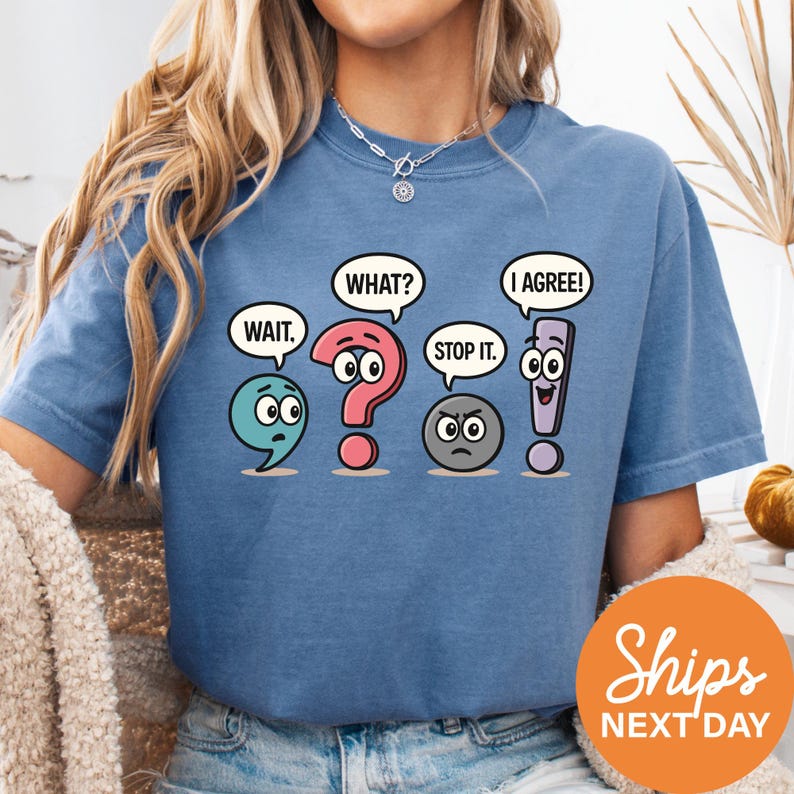 A woman wearing a blue t-shirt with a graphic design depicting four cartoon characters engaged in a conversation, with speech bubbles and facial expressions.